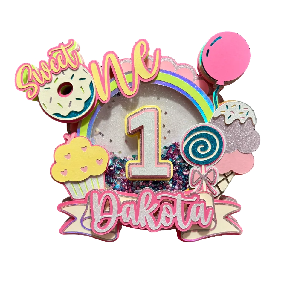 Decorative birthday cake topper with colorful text and sweet treats, held by a hand.