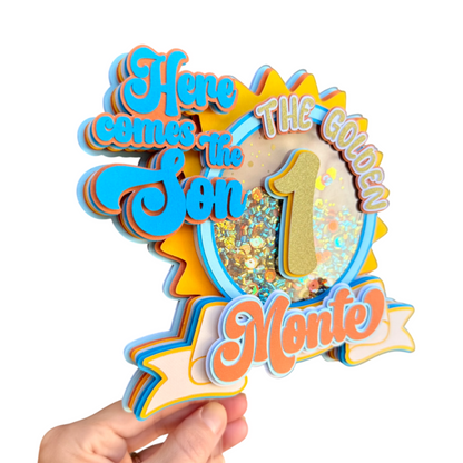 Decorative birthday sign with text 'Here comes the Son, The Golden 1, Monte' held by a hand on a white background.