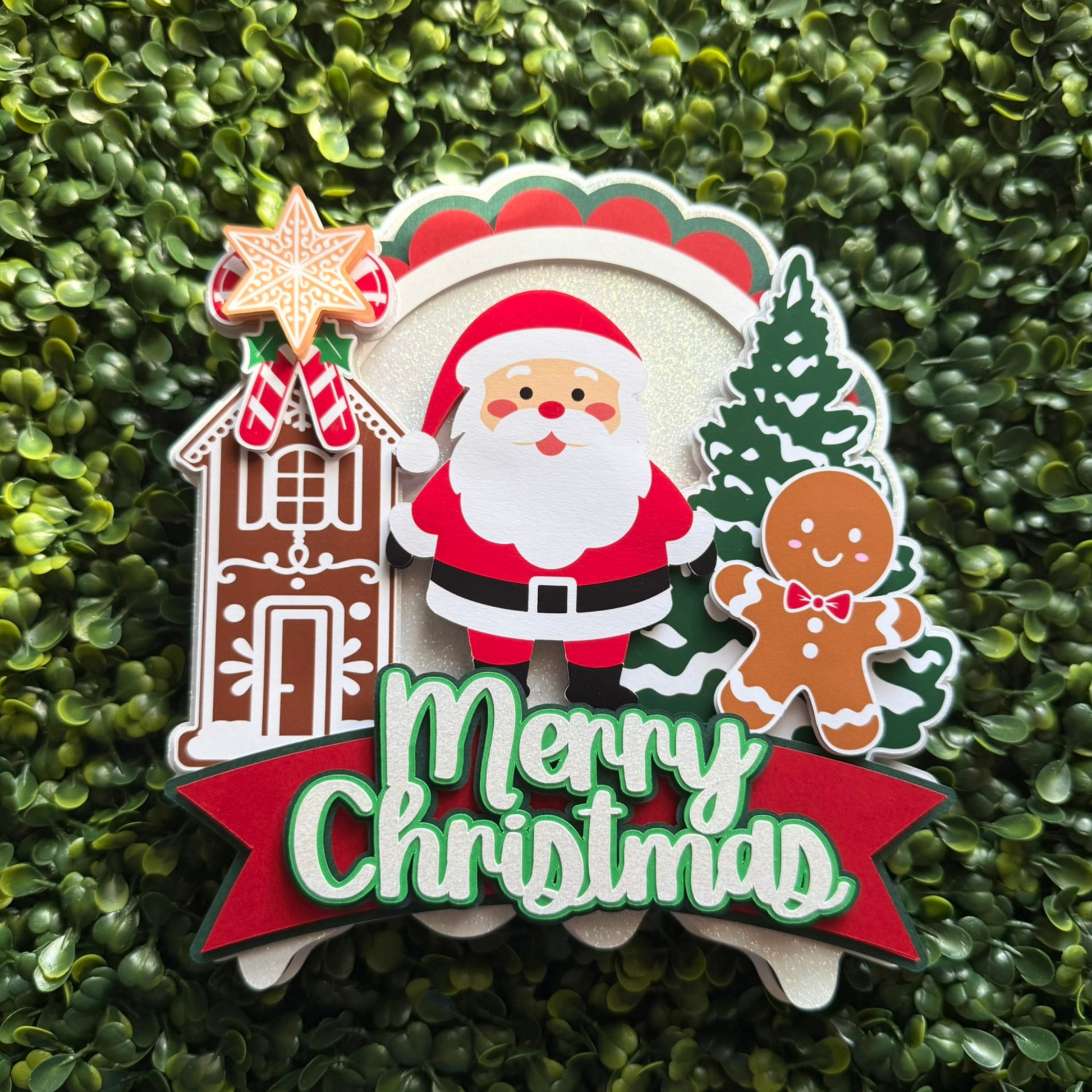 Christmas-themed decorative cake topper with Santa Claus, gingerbread man, and house on a green background
